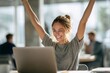 © Microstocke - Woman celebrating success with arms raised in modern office