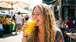 © Natalya - Cheerful young woman enjoying a refreshing juice while laughing at an outdoor market