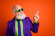 © deagreez - Elderly man in a purple suit and green shirt points up with style and confidence