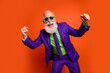 © deagreez - Bearded elderly man in purple suit green shirt and tie dances with fists up against bright orange background