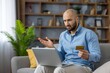 © Liubomir - Frustrated man making an online purchase using a laptop at home, experiencing issues with his credit card transaction or payment, resulting in a declined payment