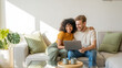 © BOTAHRY DEX - Multiracial young couple watching computer laptop sitting on the sofa at home - Happy diverse husband and wife using pc online services - Technology life style concept