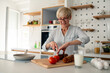 © Dorde - Smiling senior woman preparing fresh breakfast indoors in bright modern kitchen enjoying morning work from home