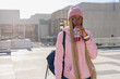 © wavebreak3 - African American woman wearing pink beanie hoodie standing on rooftop sipping red drink, copy space