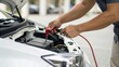 © adaptable_ Lark98A1 - A person is using jumper cables to connect a car battery under the hood of a vehicle.