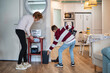 © C&A - Eighty-year-old grandmother spending quality time with her grandson, teaching him to do household chores together in a modern kitchen, promoting responsibility and family connection