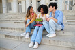 © Ladanifer - Diverse young students sitting on university stairs, eating healthy lunch and talking, enjoying a break