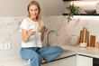 © brizmaker - Woman uses smartphone while sitting at kitchen counter with a cup