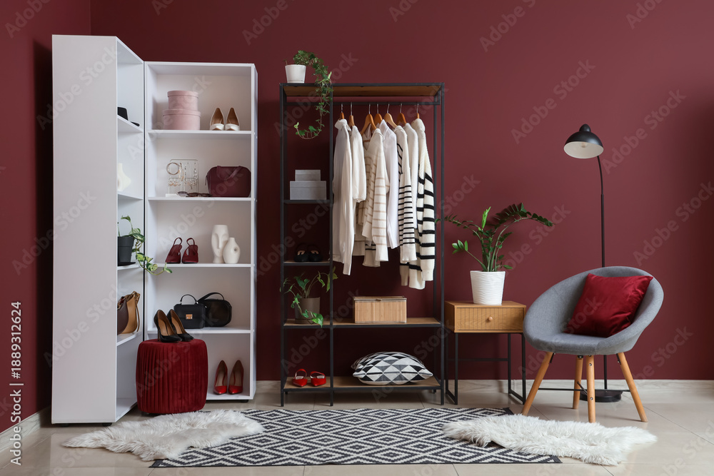 Interior of dressing room with clothes rack, armchair and shelf unit ...