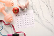 © Pixel-Shot - Composition with paper calendar, sports equipment and headphones on light background