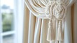 © tiger - close up of elegant creamy beige curtains tied back with decorative braided rope tiebacks in a softly lit room