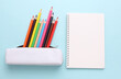 © splitov27 - White pencil case mockup with colored pencils and notebook on a blue background