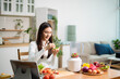 © laddawan - Healthy Asian woman making detox smoothie at home kitchen, adding fresh fruits and vegetables to blender. Clean eating, nutrition diet, wellness lifestyle