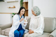© Nuttapong punna - Female doctor explaining ear anatomy to elderly woman during home medical consultation. Hearing care, senior health, audiology, prevention, wellness and healthcare