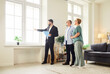 © Studio Romantic - Realtor and agent guide a senior couple through new apartment during a tour and viewing, helping buyers assess the interior and showing key home features. Real estate market and buying property.