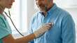 © DebbyMelindaYanti - A caring healthcare professional uses a stethoscope to listen to a mature male patient's chest during a routine medical examination in a clinic