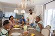 © wavebreak3 - African American family gathering around dining table in kitchen with lemonade, bread, corn, fruit