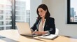© Isuru - Professional woman working on laptop at office desk