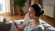 © Babb - Young caucasian female relaxing with headphones and smartphone on sofa in cozy room