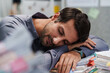 © weedezign - Asleep and tired overworked male takes a nap on document stacks, appearing lazy as he rests exhausted while overloaded working in office.