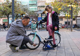 Father and nine year old child pumping wheels of a kid's bicycle outdoors, family activity and childhood