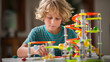 © Annamorphosis - Young boy concentrating on building a colorful marble run toy
