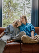 © olezzo - Lesbian couple cuddling on sofa at home, LGBT family and Valentine’s Day concept