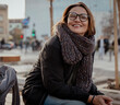 © olezzo - Portrait of happy mature woman wearing glasses and warm scarf outdoors, confident look at camera