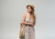 © Volodymyr_sh - Thoughtful young woman with reusable grocery bag looking away wearing straw hat and summer dress in studio