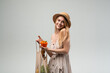 © Volodymyr_sh - Smiling young woman holding orange bell pepper and reusable mesh shopping bag, sustainable lifestyle and healthy food concept