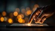 © horizon - Close-up view of a finger touching a glowing digital tablet screen with detailed skin texture against a warm background of soft bokeh lights.