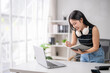 © Wasana - Young asian businesswoman taking notes in notebook while working at office