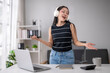 © Wasana - Young woman enjoying music while working remotely
