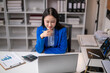 © Wasana - Asian businesswoman working with laptop and financial chart at office desk