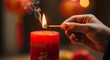 © Manusia - Close-up of a hand delicately lighting a traditional red candle with a matchstick, its warm glow illuminating auspicious symbols and embodying cultural heritage and hopeful celebration
