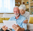 © Lumos sp - Portrait of a lovely senior mature couple together holding a tablet on sofa at home