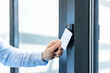 © Liubomir - Hand holding white access card to an rfid reader, unlocking an electronic office door for secure, contactless entry and employee identification in a modern corporate building