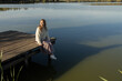 © Anna - happy young European woman in her twenties enjoys relaxing outdoors on wooden pier on sunny day. feels good, positive outlook. . Vitality, freedom, and joy, loving life. Space for text.