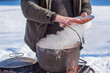 © T.Den_Team - Person preparing hot food outdoors during winter using a metal cauldron over open fire. Close view of hands cooking a meal in cold weather