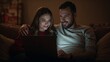 © Future Vision - Watching laptop, couple on sofa at home, woman-left red-top, man-right gray-shirt watch arm-around
