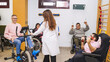© DMegias - Diverse group of people with disabilities engaged in physical therapy exercises with a physiotherapist in a bright clinical setting