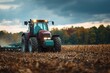 © Iftikhar alam - Farm vehicle works in mature crop field under partly cloudy sky during late afternoon in autumn landscape