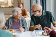© Halfpoint - Elderly couple having lunch in community center cafeteria.