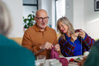 © Halfpoint - Group of senior people learning knitting together with caregiver tutor in a community center.