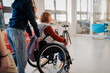 © Halfpoint - Schoolmate pushing girl in wheelchair on school hallway.