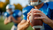 © Nataliya - Group of american football players in action during game, faceless athletes, blue jersey foreground, throwing ball process, sports competition, defocused field, with copy space
