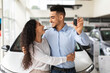 © Prostock-studio - Loving arabic couple standing next to luxury white car and hugging at dealership automobile salon, showing key from their new auto, cheerfully smiling at each other and hugging, closeup