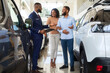 © Prostock-studio - Car Salesman Advertising New Car To Young Black Spouses In Dealership Center, Professional Salesperson Helping African American Family To Choose New Automobile In Salon, Showing Auto Models