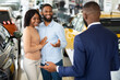 © Prostock-studio - Young Black Couple Talking To Salesman In Dealership Office While Buying New Car, Happy African American Spouses Discussing Automobile Models With Salesperson In Showroom, Selective Focus