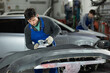 © JackF - Adult male mechanic in uniform polishes bumper of car with machine in car service station